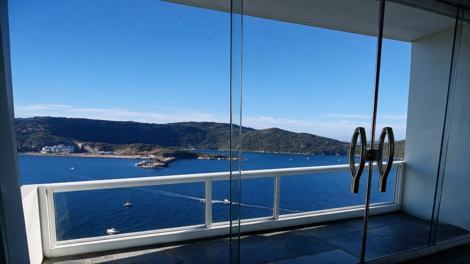 Vista da varanda: enseada com barcos, a Praia do Forno e a ilha ao fundo